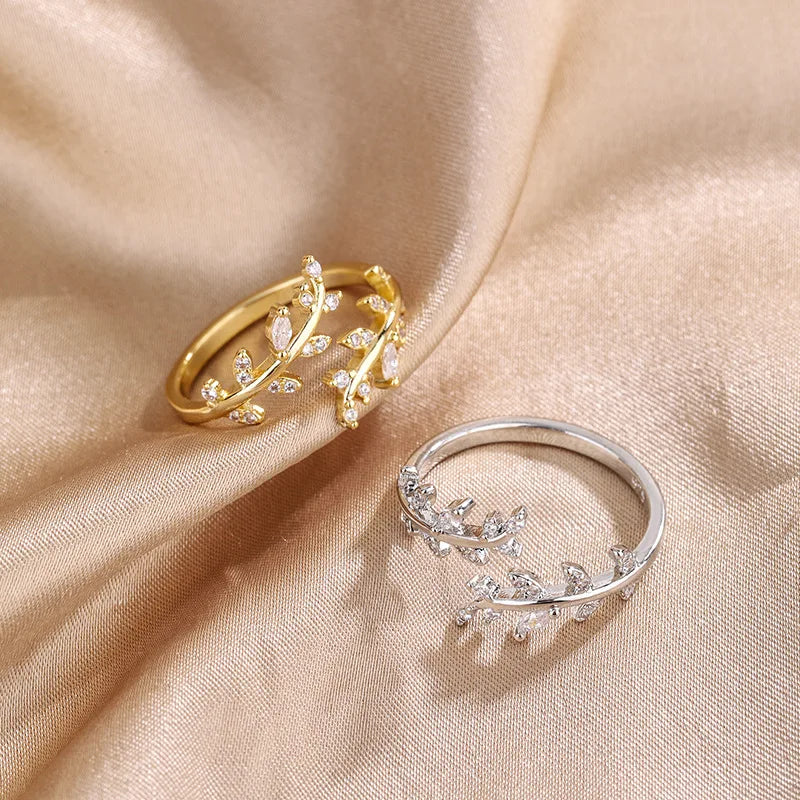 Gold and silver rings with leaf designs on a beige fabric background